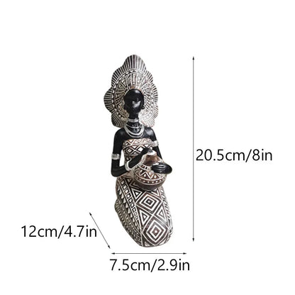 Seated African resin woman statue in black and white tribal dress with headpiece, 20.5cm tall, holding pot