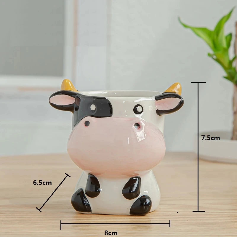 Ceramic cow-shaped planter holding a green succulent, displayed on a wooden surface.
