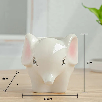 Ceramic elephant-shaped planter holding a green succulent, displayed on a wooden surface.