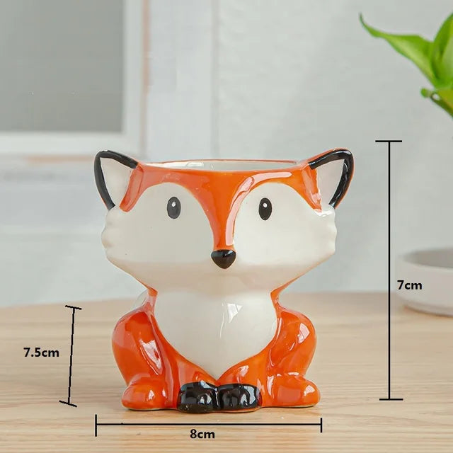 Ceramic fox-shaped planter holding a green succulent, displayed on a wooden surface.




